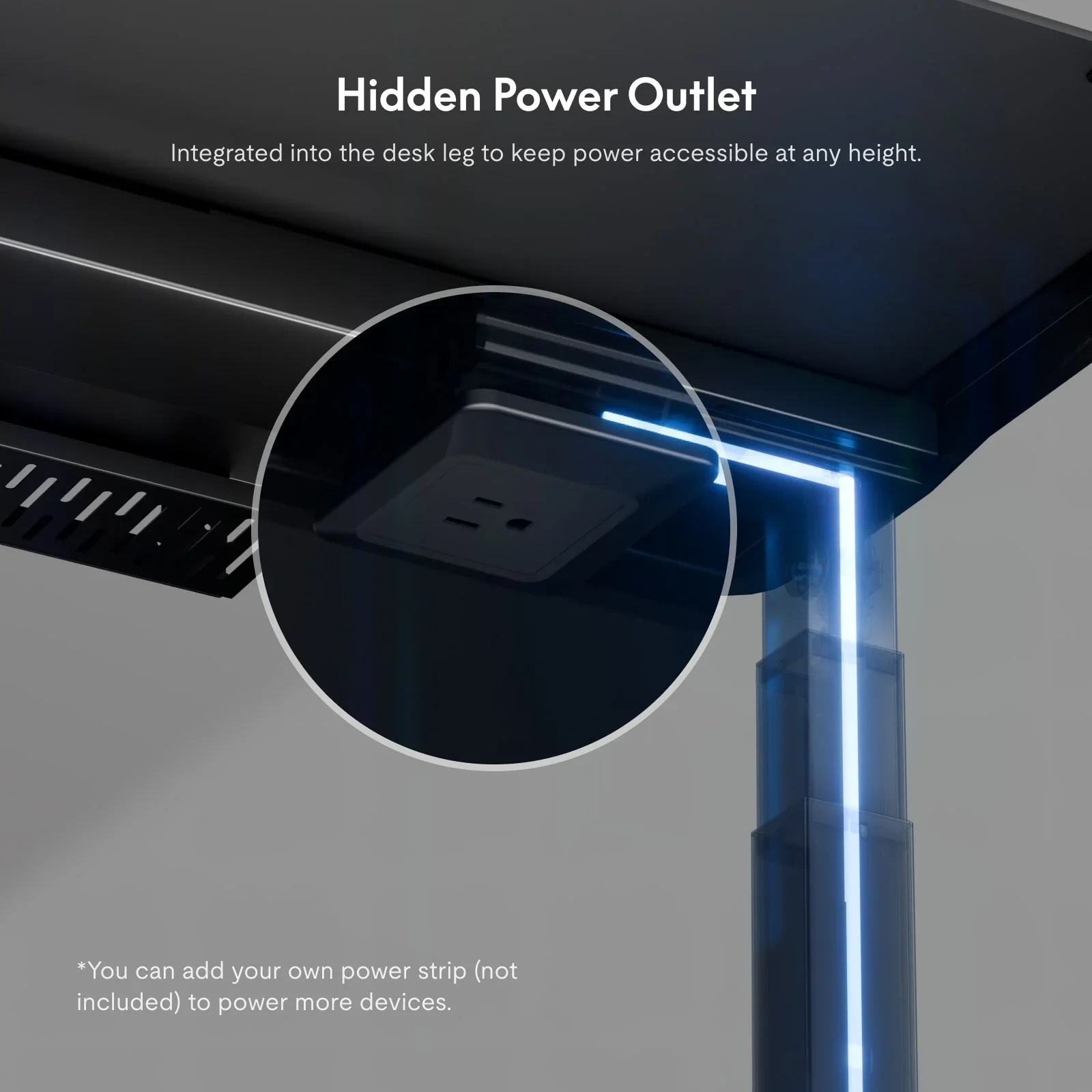 Under the desktop with a magnified circle showing a power socket built into the top of the leg, plus a headline and a footnote about adding a power strip.