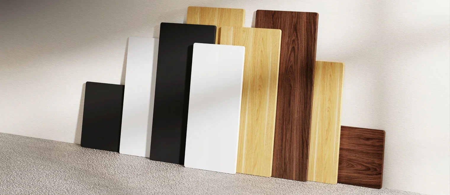 Row of laminate desktops in black, white, maple and walnut finishes leaning against a wall.
