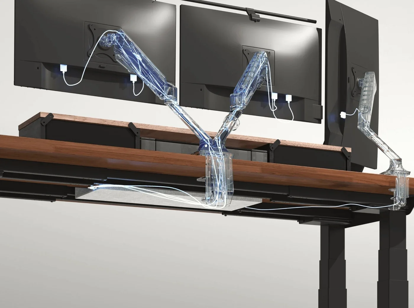 Render of three monitors on see-through arms clamped to a walnut desktop, showing cables routed through the arms down to a cable tray under the desk.