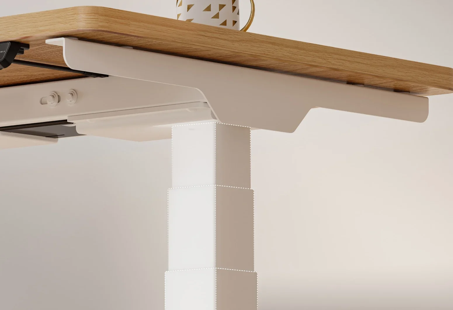 Low-angle close-up of the white E7 Mini leg column meeting the frame bracket under a light oak top, with a mug on the desk edge.