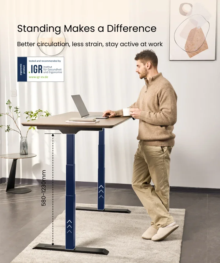 Man standing at a black-frame walnut desk with blue-highlighted legs and a 580–1230 mm height arrow, headline "Standing Makes a Difference" and a FlexiSpot badge.
