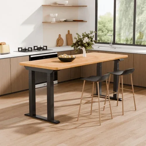 E7 Plus Max raised to counter height with a light bamboo top and black frame used as a kitchen island with two bar stools and a fruit bowl.