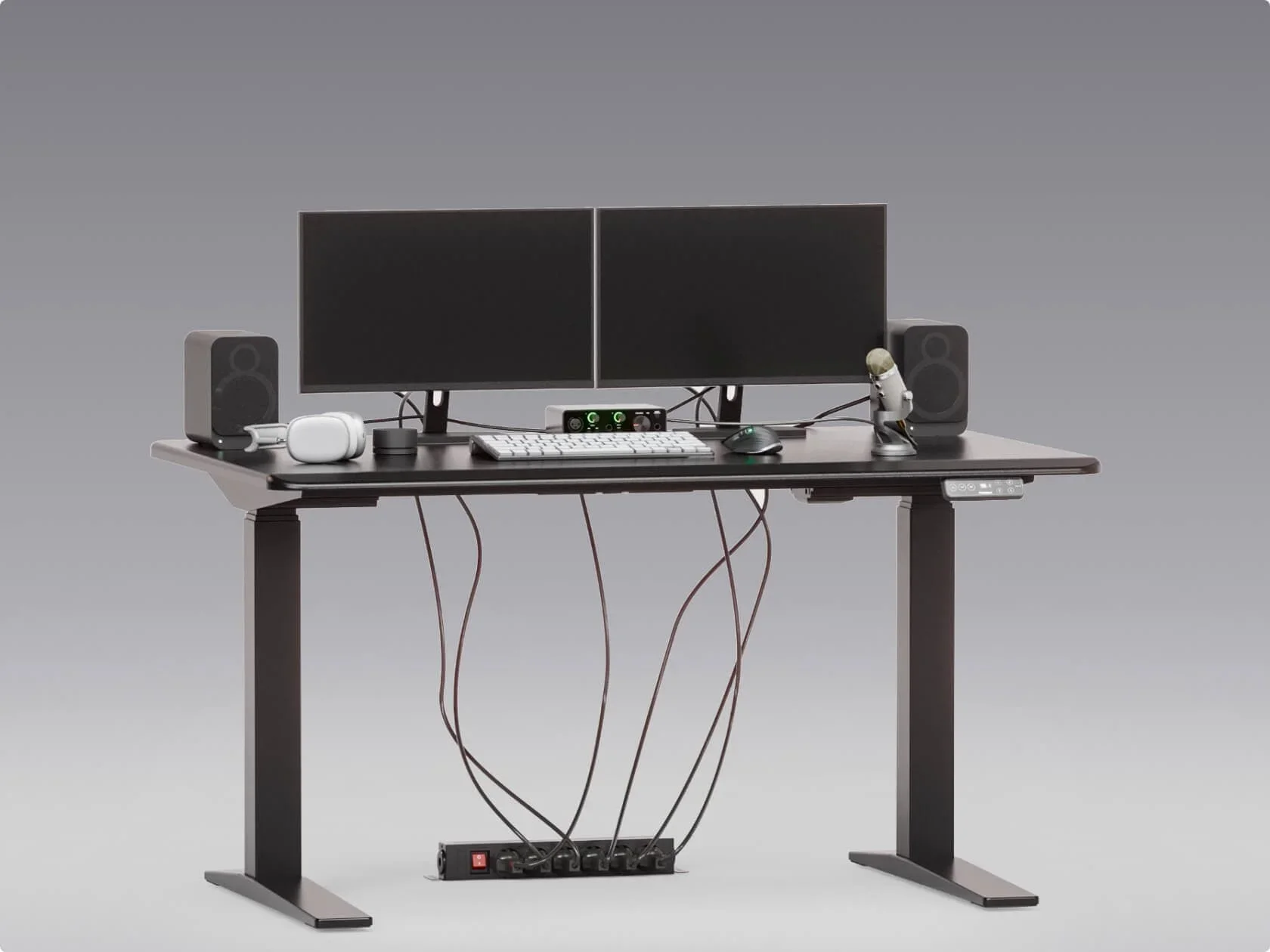 Studio render of the black desk with dual monitors and cables dangling to a floor power strip (the "before" of a before/after pair).