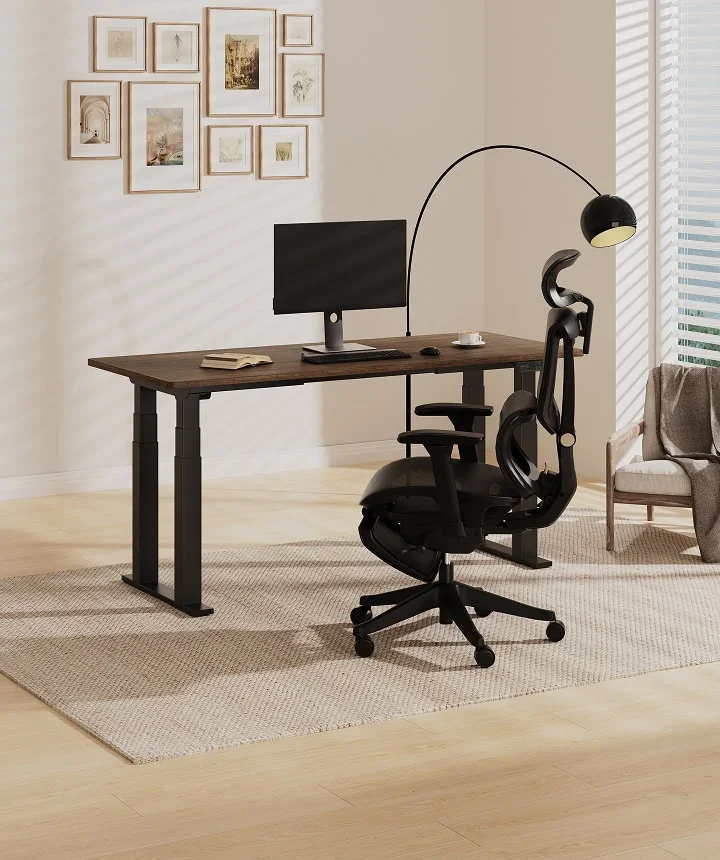 E7 Plus with a dark walnut top, monitor and black mesh chair in a warm room with framed prints and an arc lamp.