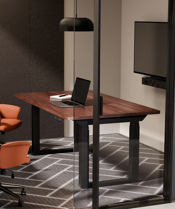 E7 Plus Max with a dark walnut top in a glass-walled meeting room with orange chairs and a wall TV.