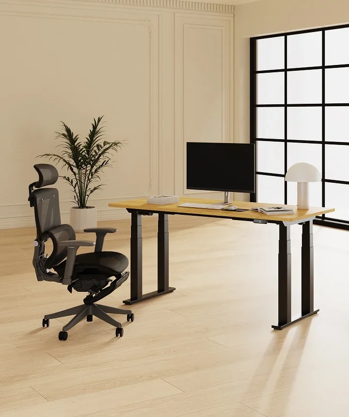 E7 Plus with an oak top, monitor and grey mesh chair in a bright room with tall black-framed windows.