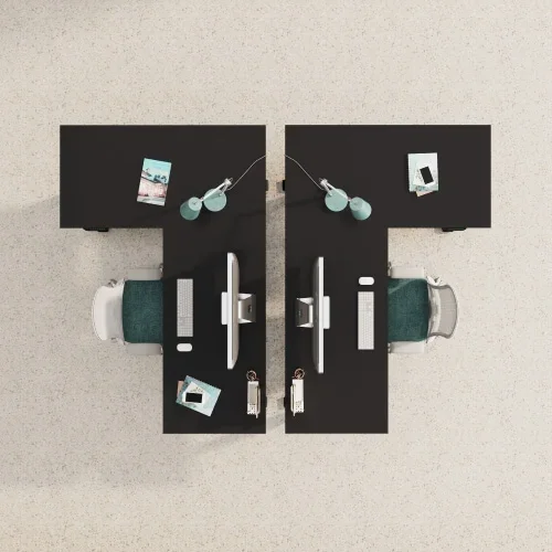 Top-down view of two black L-desks placed back to back in a T layout on beige carpet, with green chairs, monitors and desk props.