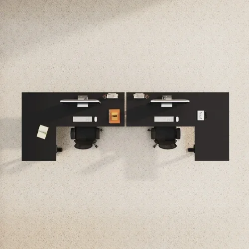 Top-down view of two black L-desks side by side facing the same way on beige carpet, with black chairs, monitors and desk props.