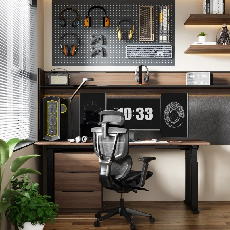 E7 Plus with a dark walnut top and black four-leg frame in a gaming/work nook with a pegboard of headphones and controllers, a large clock display, PC tower, drawer unit and mesh ergonomic chair.