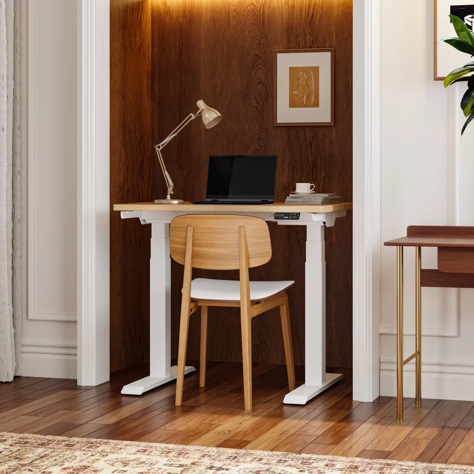 White-frame E7 Mini with a light oak top in a warm wood-panelled alcove with a laptop, desk lamp, framed print and a wooden chair.