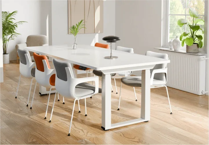 White-frame E7 Plus Max with white top as a dining/meeting table with grey and orange chairs in a bright room.