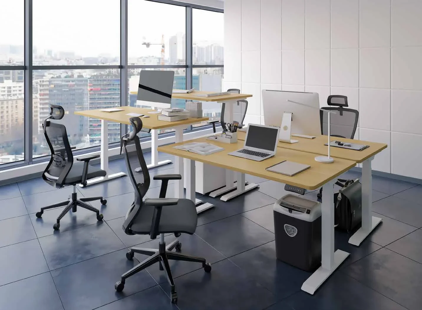 An open-plan office with three white-frame desks with oak-look tops, mesh chairs, monitors and laptops, and a city view through tall windows.