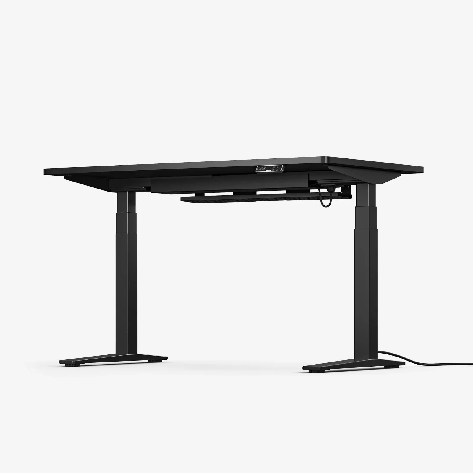 Three-quarter studio view of the all-black desk with the under-desk cable tray and keypad visible and a power cord trailing from one foot, on a plain white background.