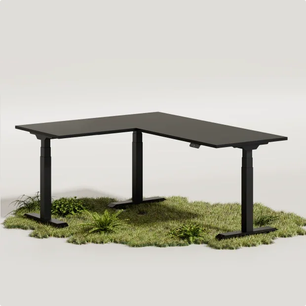 Black E7L corner desk with black top standing on a patch of moss and grass on a light studio background; no text.