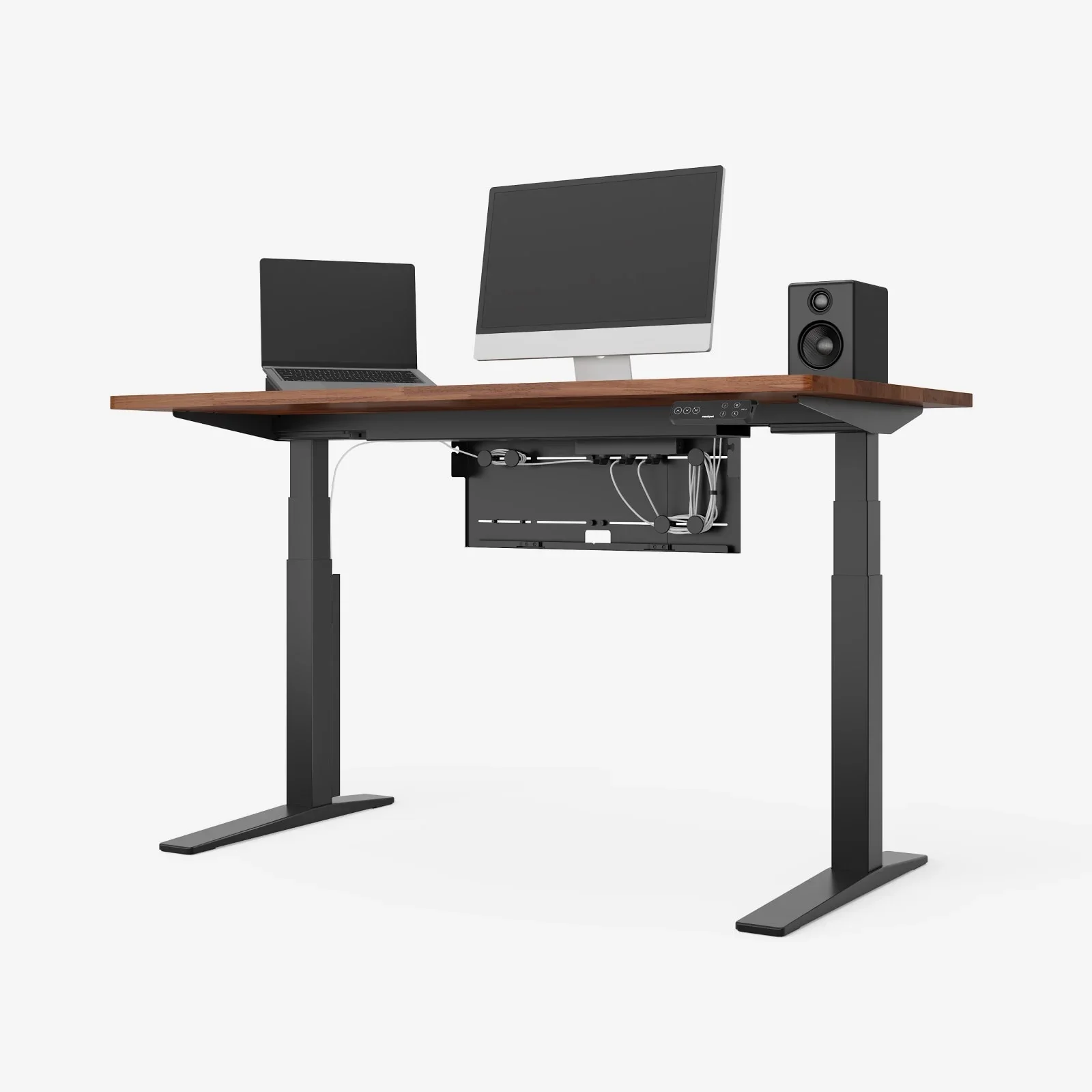 Studio shot of a black-frame desk with a walnut top holding a laptop, an all-in-one monitor and a speaker, with the cable management box hanging underneath, on a white background.